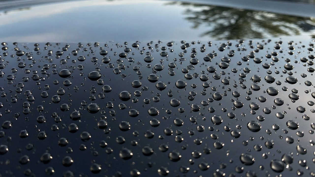 Wasser perlt in runden Tropfen auf einem frisch gewaschenen und versiegelten Autodach